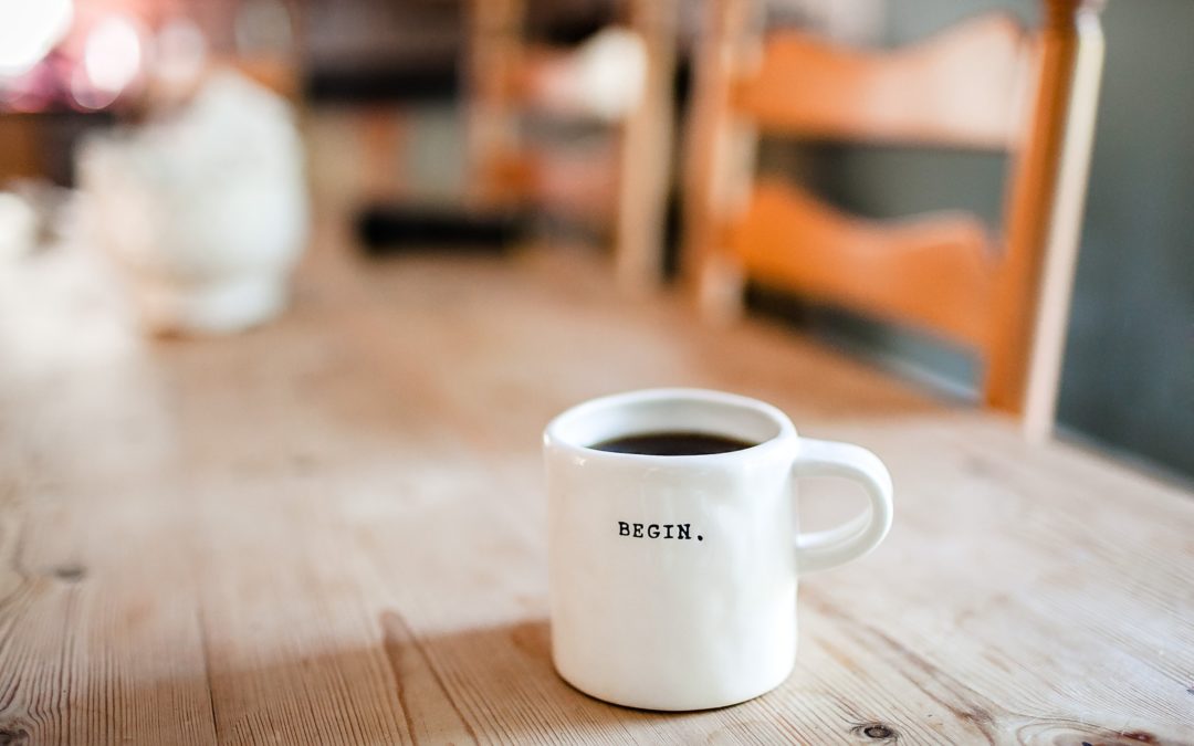 A white mug on the table with the word Begin typed in black on it