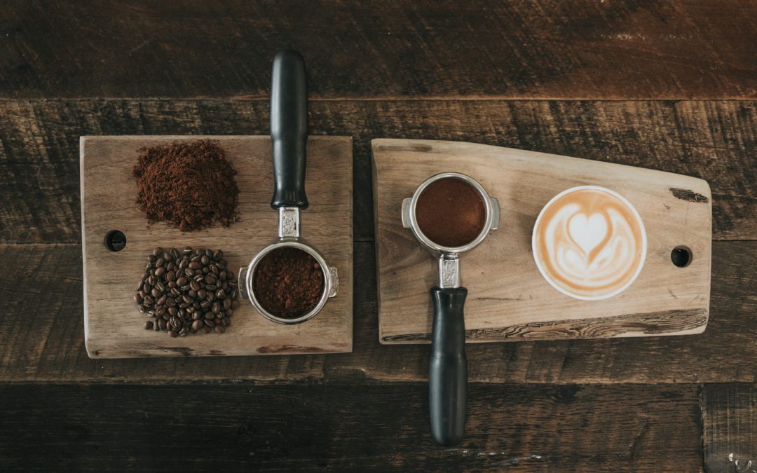 Photo of two coffee protafilters, ground and whole coffee beans and a latte