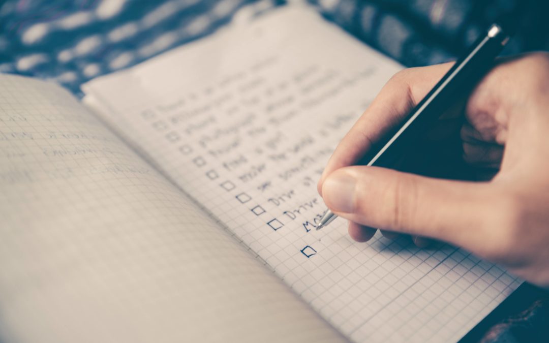 Image of a person's hand writing a todo list in a notebook