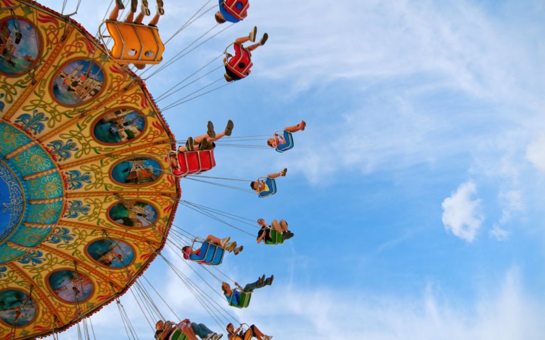 Photo taken from below of people riding on a fairground swing ride