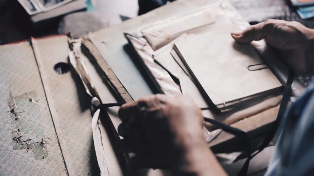 Photo of two hands sorting through old letters, photos and papers