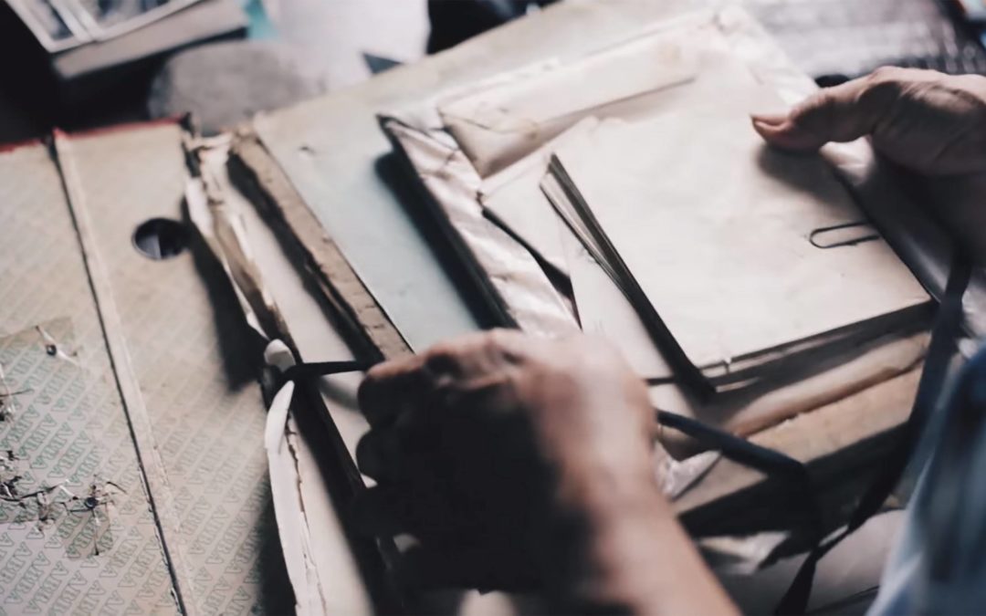 Photo of two hands sorting through old letters, photos and papers