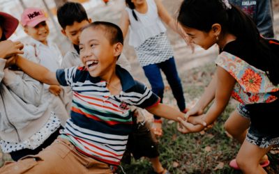 Photo of a bunch of kids paying with one little boy smiling and laughing at the forefront