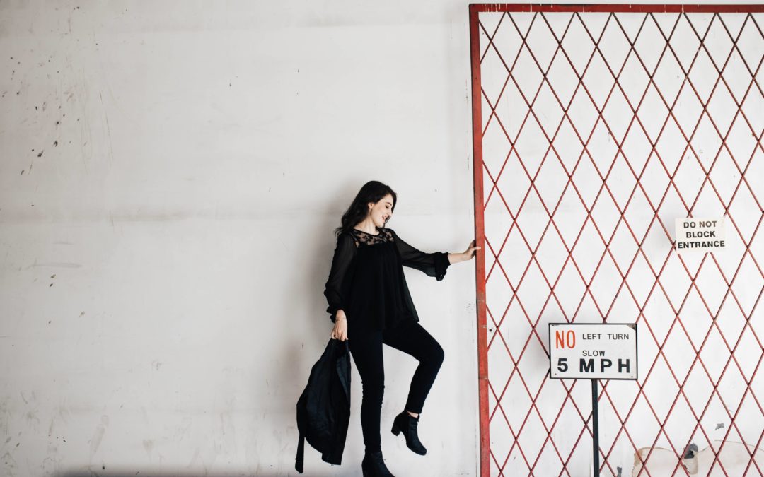 Woman dressed in black holding a gate open