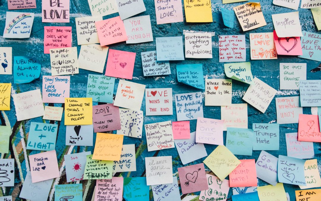 A wall covered in post-its with positive affirmations like "love trumps hate" and "be love" and "I will change the things I cannot accept"