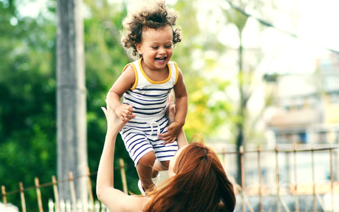 A woman holding a laughing child up in front of her