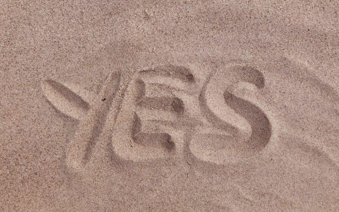 The word "Yes" drawn in the sand