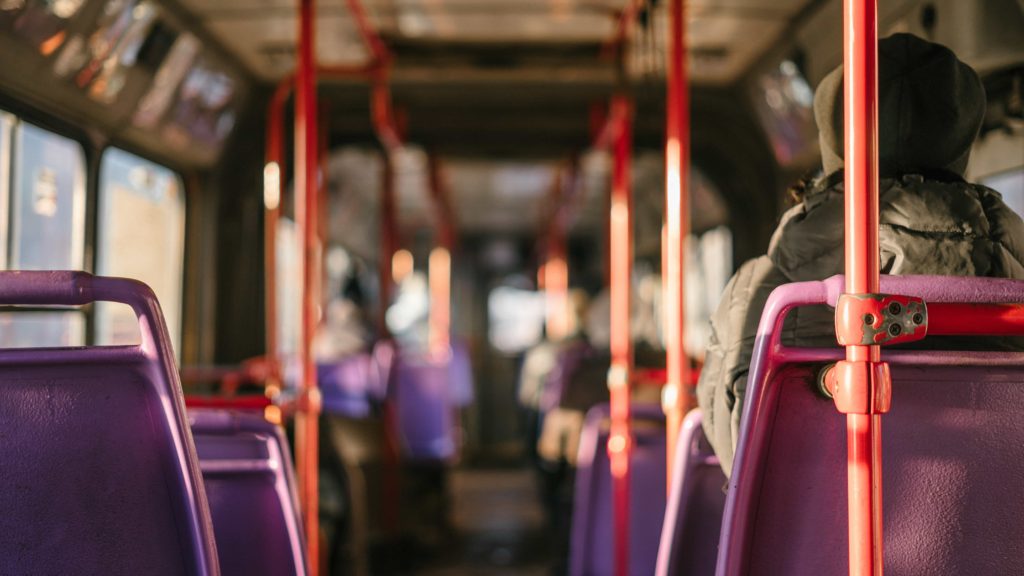 Photo of the interior of a public transit bus with red bars and purple seats