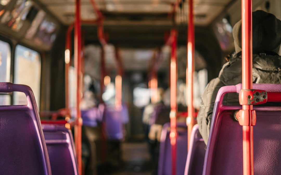 Photo of the interior of a public transit bus with red bars and purple seats