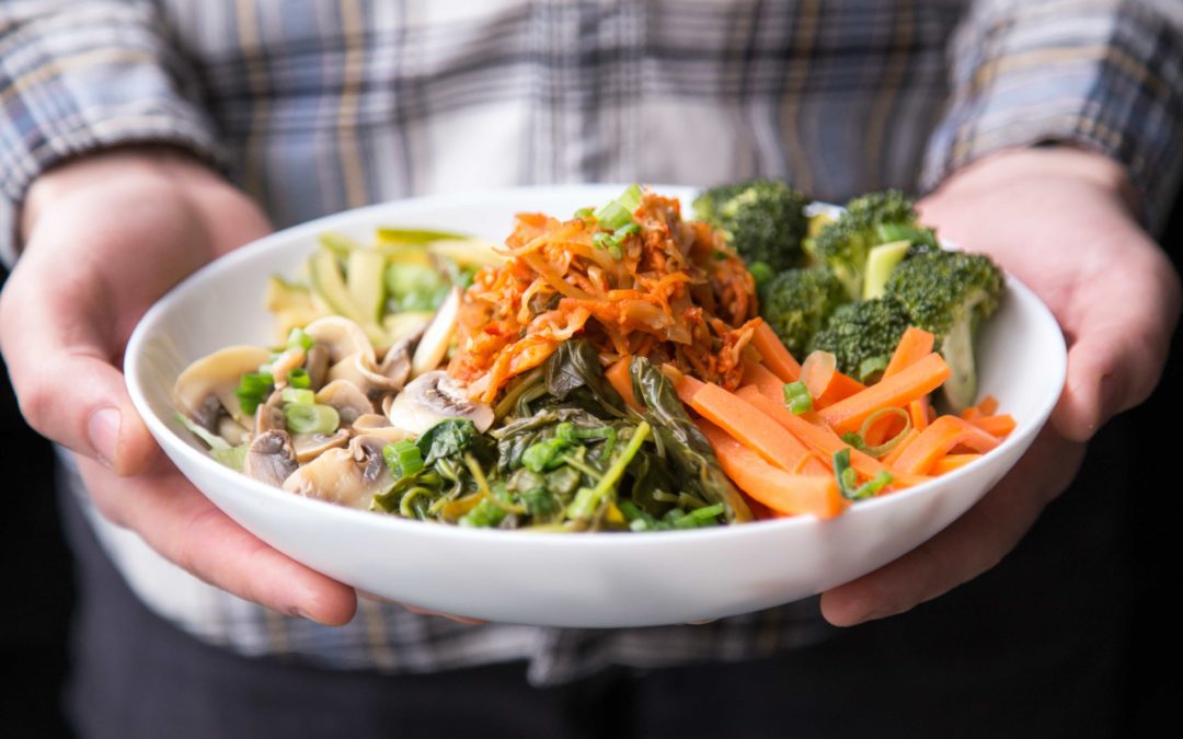 Man holding a plate of colourful vegetables with only his hands and the plate showing