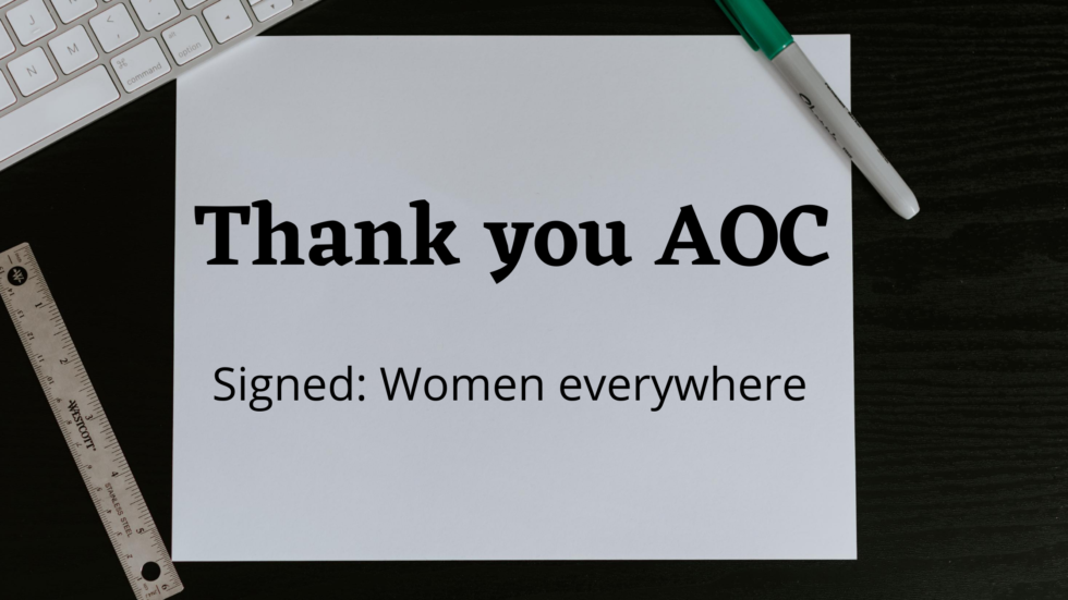 Photo of a paper on a desk with a keyboard, ruler and marker beside it that says: "Thank you AOC, Signed: Women Everywhere"