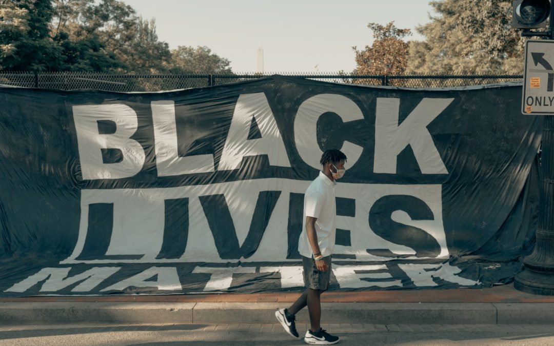 Black person walking in front of Black Lives Matter poster