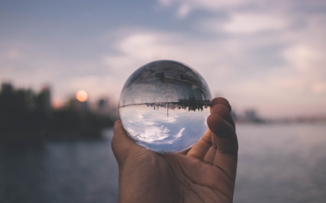 A hand holding a crystal ball with an image of Toronto upside down showing through the crystal ball